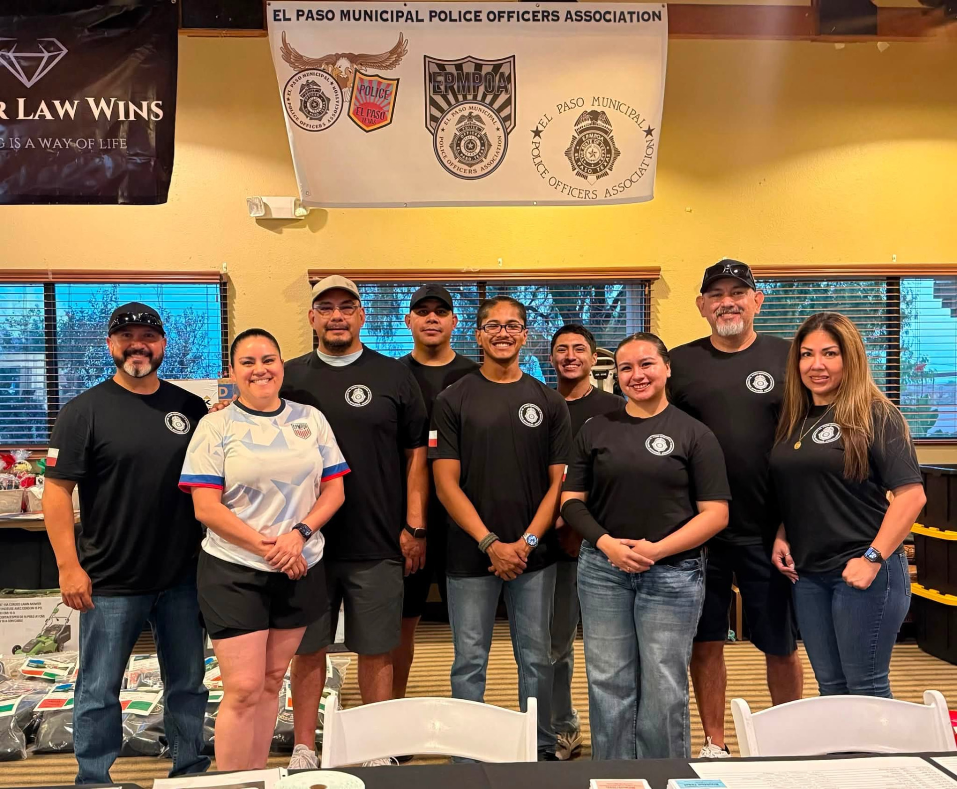 EPMPOA members and volunteers posing together under the El Paso Municipal Police Officers' Association banner at a fundraising event.